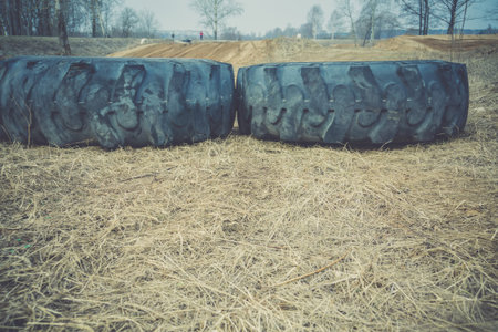 Big black rubber wheel laying on the sand, filtered background.の写真素材
