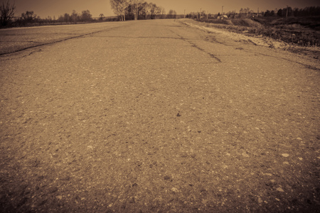 Old cracked, damaged asphalt road in countryside, vintage colors.の写真素材