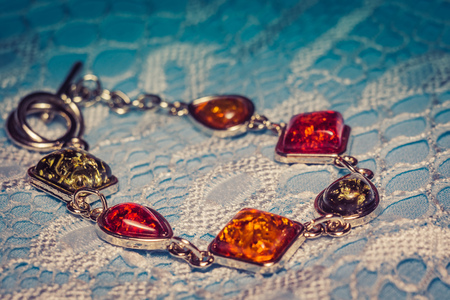 Vintage silver plated jewelry with colorful synthetic amber, filtered background.の写真素材