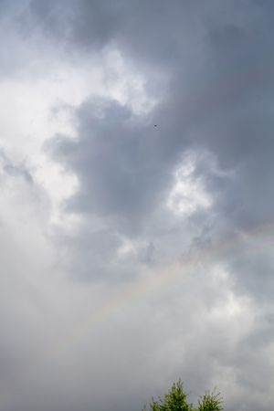 Colorful rainbow against dark cloudy sky background.の写真素材
