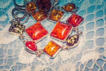 Vintage silver plated jewelry with colorful synthetic amber, filtered background.の写真素材