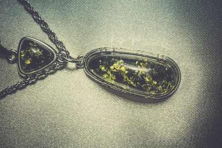 Vintage silver plated jewelry with colorful synthetic amber, filtered background.の写真素材