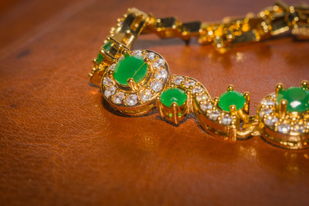 Elegant female jewelry golden bracelet with precious green gem, emerald.の写真素材
