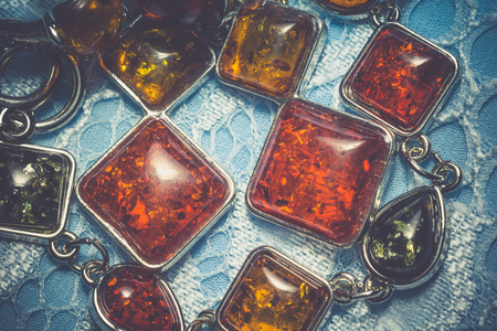 Vintage silver plated jewelry with colorful synthetic amber, filtered background.の写真素材