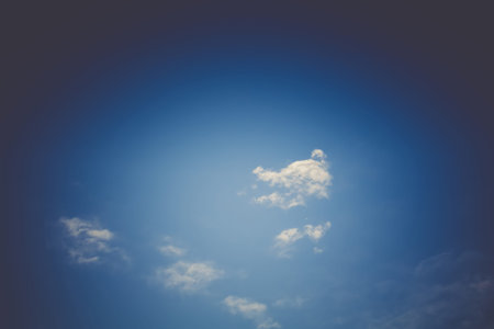 Blue sky with soft dark clouds, natural filtered background.