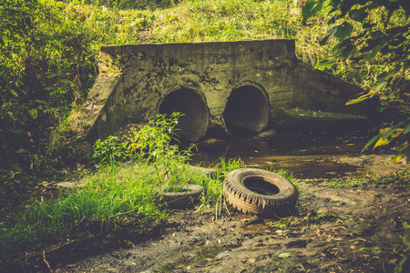 Large old concrete drain pipe, culvert in the grass, filtered background.の写真素材
