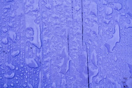 Wooden surface of violet color covered with water drops background.の写真素材