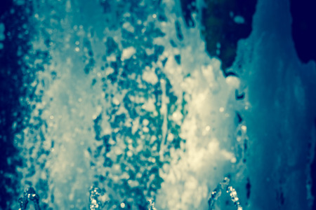 Splashing water in the city park fountain at the summer day, filtered background.の写真素材