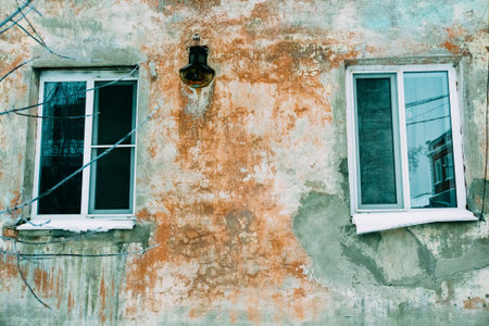 Old walls with cracked plaster and two windows.