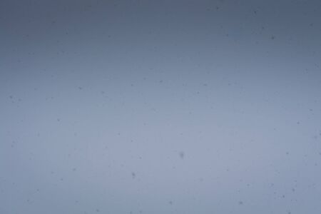 Fresh falling snow over grey sky close up background.の写真素材