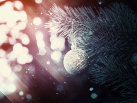 Decorative Christmas ball made of silver glitters on a spruce branch fantasy background.の写真素材