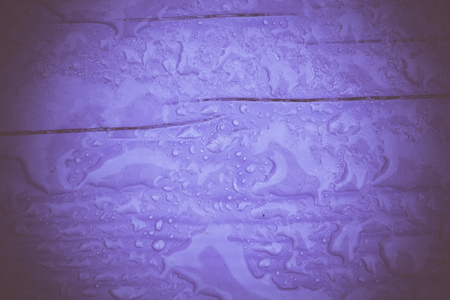 Wooden surface of violet color covered with water drops filtered background.の写真素材