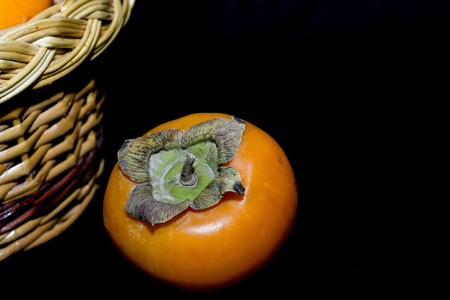 Delicious ripe persimmon, juicy orange fruits on black background.の写真素材