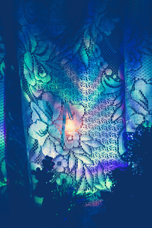 Defocused colorful garland lights reflection on white curtains background.の写真素材