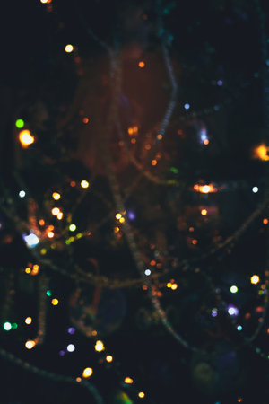 Decorated Christmas tree and colorful garland lights, defocused background, bokeh effect.