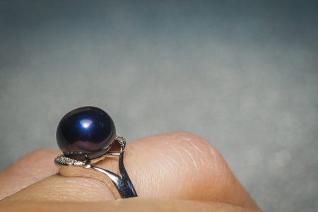 Luxury silver ring with natural freshwater pearl of black color, macro.