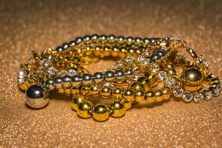 Decorative fashion gold bracelets set on glitter background.の写真素材