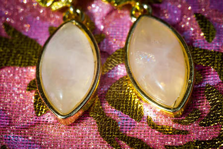 Fashion yellow gold earrings decorated with rose quartz on pink background.の写真素材