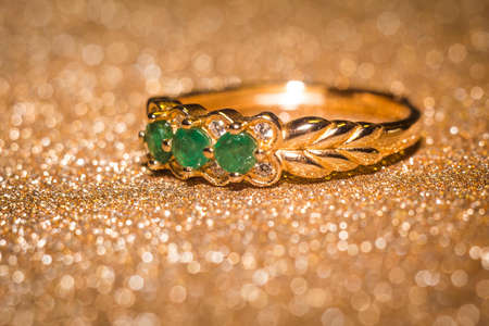 Fashion gold ring with natural green emerald on glitter background.の写真素材