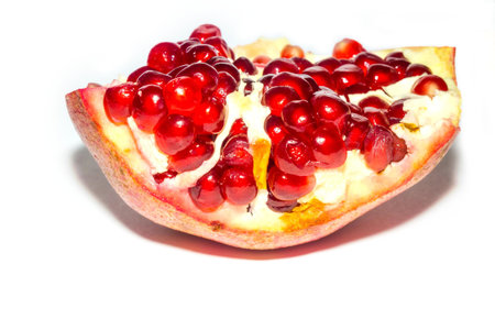 Part of fresh ripe pomegranate with seeds on white background.