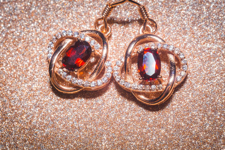 Fashion golden earrings with a dark red garnet stone.の写真素材