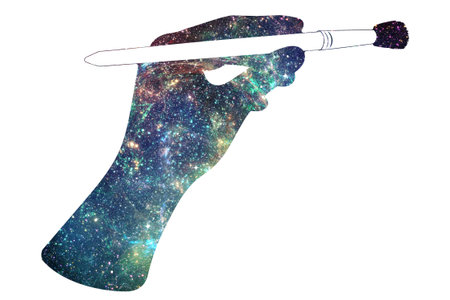 Human hand holding paintbrush and abstract starry space design.