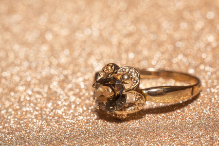 Rose gold fashion ring decorated with dark brown smoky quartz over glitter background.の写真素材