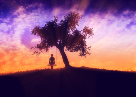 Silhouette of a girl on a swing under the big tree at sunset time.の写真素材