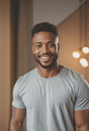 Young, handsome dark skinned man smiling at the viewer, modern hairstyle, gray melange t shirt.の素材
