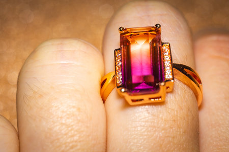 Fashion golden ring with pink yellow stone, close up background.の写真素材