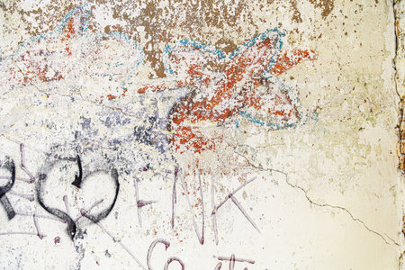 Distressed white paint on the wall with some graffiti, abstract texture as grunge background.の写真素材