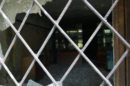 Old metal grille on the window of the empty store. Broken and abandoned store building in the rural town.の写真素材