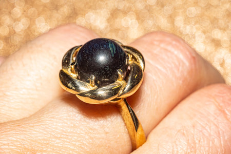 Macro photo with yellow gold ring with a round hawk's eye stone. This elegant photo is perfect for jewelry enthusiasts, fashion blogs, and design projects seeking a touch of sophistication and style.の写真素材