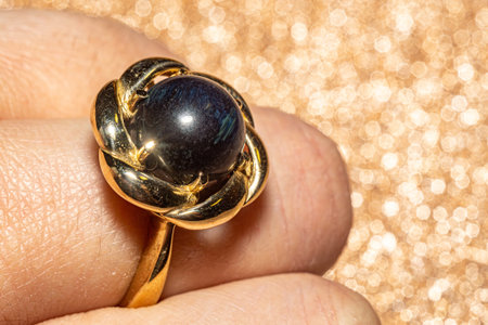 Macro photo with yellow gold ring with a round hawk's eye stone. This elegant photo is perfect for jewelry enthusiasts, fashion blogs, and design projects seeking a touch of sophistication and style.の写真素材
