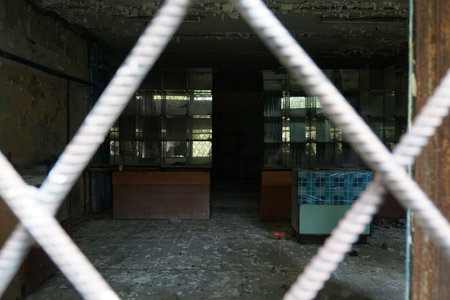 Old metal grille on the window of the empty store. Broken and abandoned store building in the rural town.の写真素材