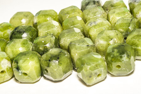 Beautiful green jade beads in macro photography, perfect for crafting and jewelry design. Decorative faceted square shape jade stone beads for boho jewelry.の写真素材