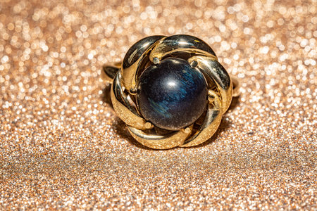 Macro photo with yellow gold ring with a round hawk's eye stone. This elegant photo is perfect for jewelry enthusiasts, fashion blogs, and design projects seeking a touch of sophistication and style.の写真素材