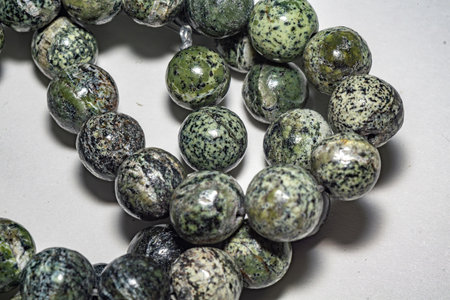 Delicate and charming spotted green serpentine beads, ideal for jewelry, crafts, or decor. Close up photo, perfect for enhancing various creative projects. Decorative beads of natural serpentine beadsの写真素材