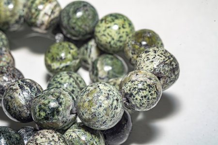 Delicate and charming spotted green serpentine beads, ideal for jewelry, crafts, or decor. Close up photo, perfect for enhancing various creative projects. Decorative beads of natural serpentine beadsの写真素材