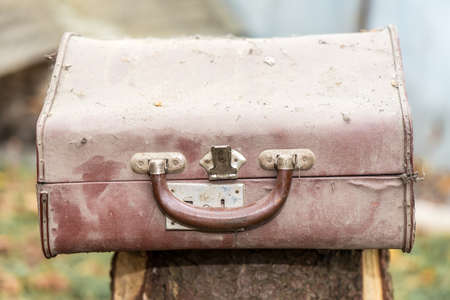 Front view of brown dirty and dusty vintage suitcaseの写真素材