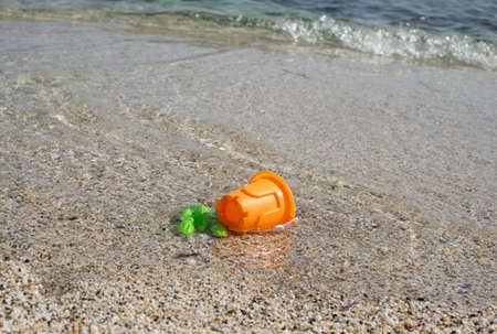 Green and orange plastic toys in the seawaterの写真素材