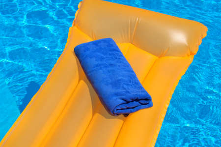 Blue towel on an orange inflatable mattress floating in the poolの写真素材