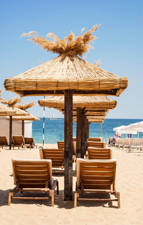 Straw umbrellas and beach chairs on a beautiful beachの写真素材
