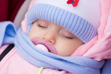 Muffled baby sleeping with dummy in mouth