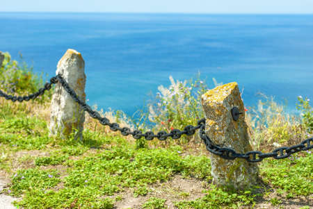 Old fence with chain near the seaの写真素材