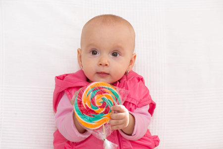 Little baby girl portrait with colorful lollipop