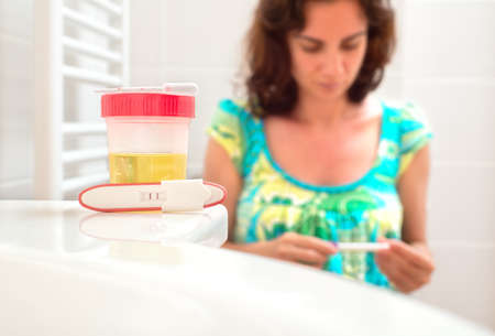 Young woman doing pregnancy test in the toiletの写真素材
