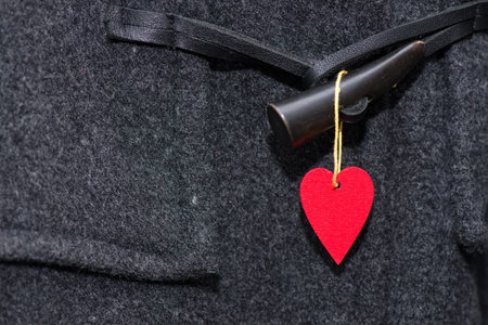 Red heart hanging on a button of a coat