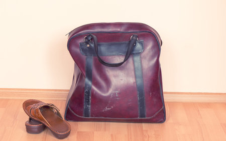 Old leather bag and two slippers indoors