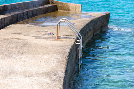 Pink slippers on the pier near the seaの写真素材